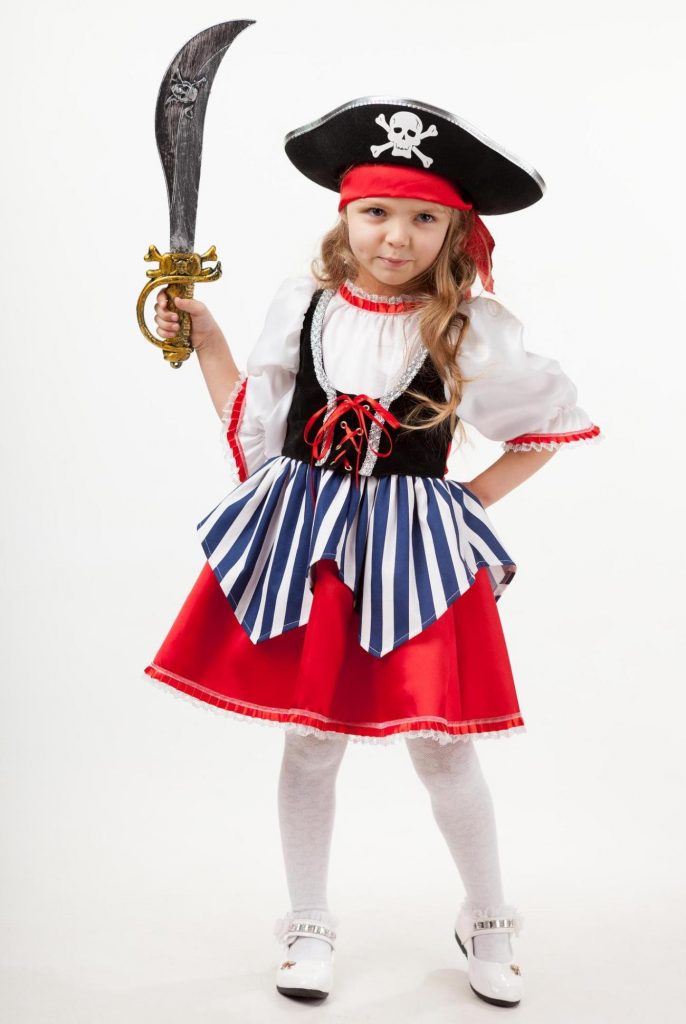 Піратський костюм: блузка, плаття з корсажем та двошаровою спідницею, на голові – трикутний капелюх з черепом поверх бандани, у руці – іграшкова шабля