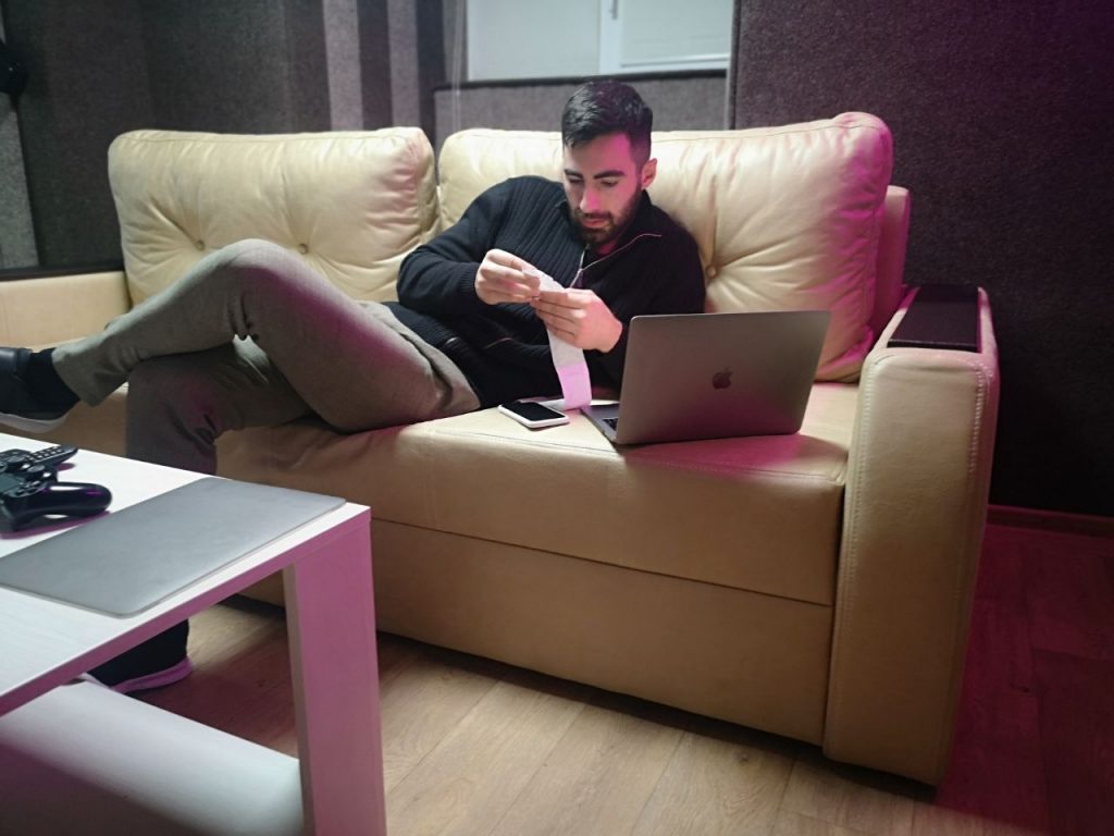 Парень сидит на диване с компьютером в клубе Lumiere